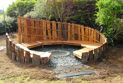 image d'une structure circulare en bois. Les palettes entourant le cercle et une surface surelevé du sol en bois est faite pour s'asseoir.